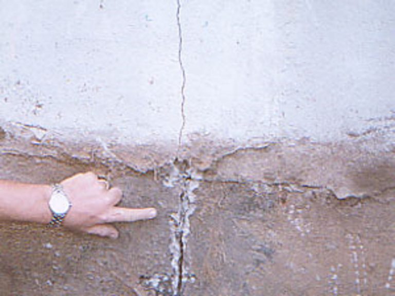 Fissure de béton dans mur de fondation on voit la portion sous le niveau du sol.