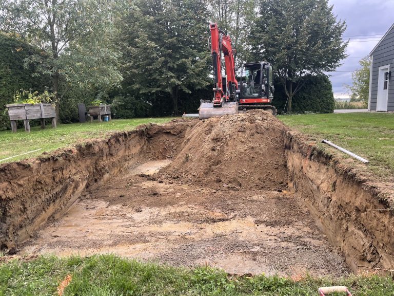 Une pelle excavatrice qui termine un trou d'excavation de plus ou moins 4 pieds de profond pour l'installation d'un champ d'épuration.
